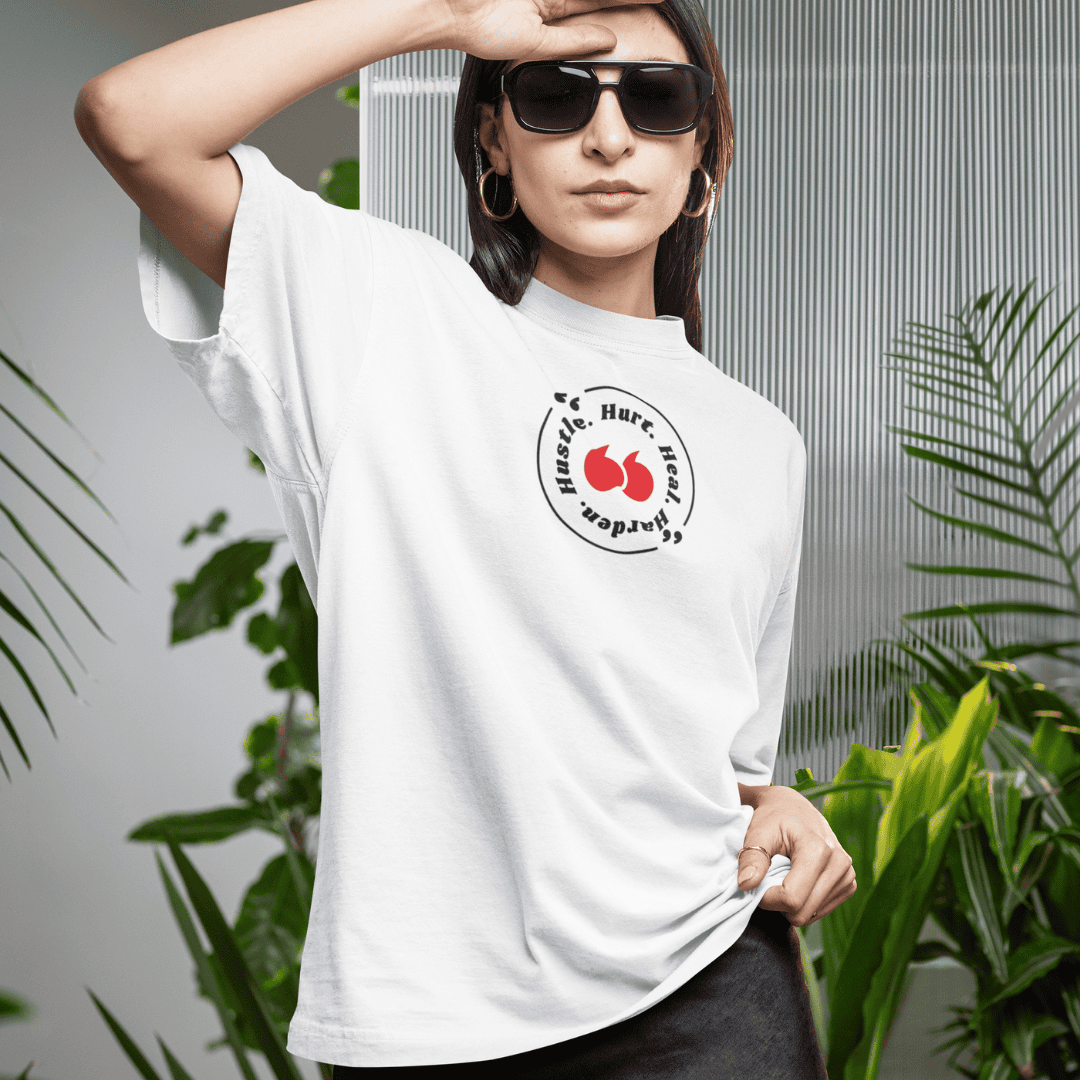 Person wearing a white t-shirt with a logo, standing among plants. wordsarmor