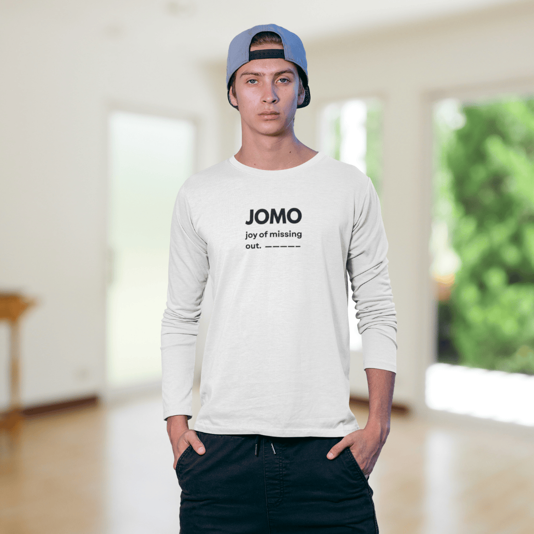 Person wearing a white long-sleeve shirt with 'JOMO' text, standing in a bright room. wordsarmor