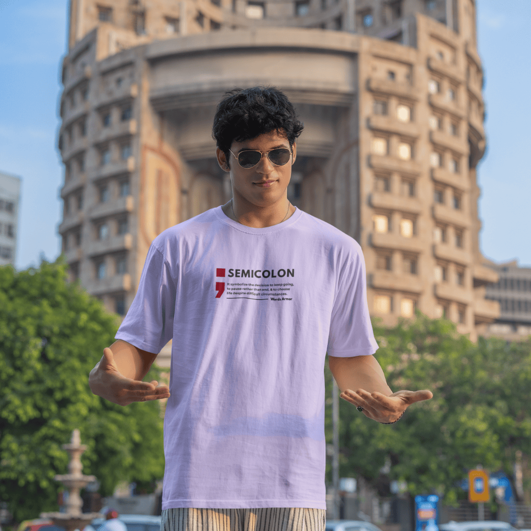 Person wearing a lavender t-shirt with a visible semicolon brand logo in an urban setting wordsrmor