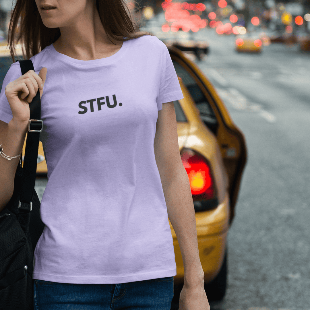 Person wearing a lavender purple t-shirt with 'STFU.' text on a city street. wordsarmor