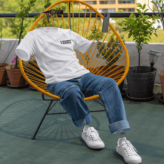 Person wearing a white t-shirt with text and blue jeans sitting on a yellow chair outdoors wordsarmor.