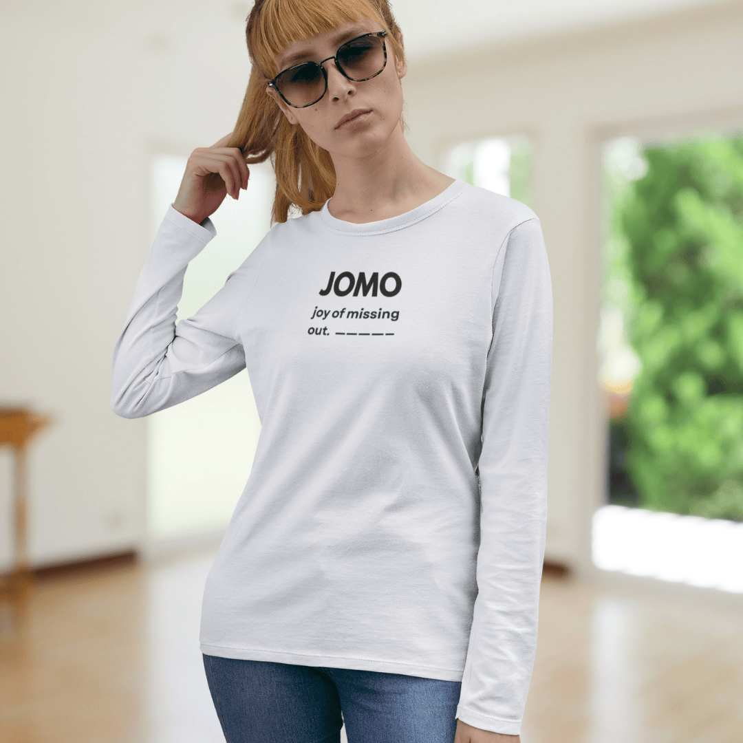 Woman wearing a white long-sleeve shirt with 'JOMO joy of missing out' text. wordsarmor